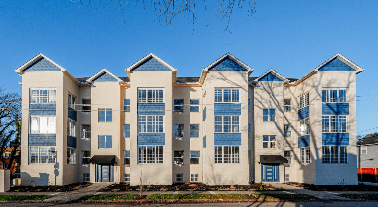 A tall apartment building with numerous windows, overlooking a bustling city street.