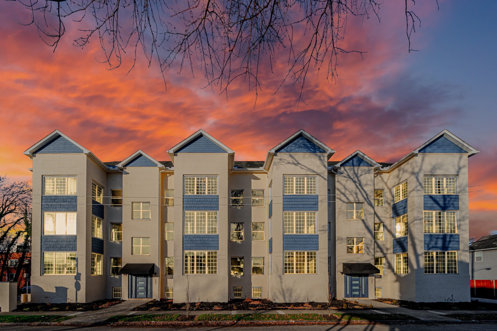 The image features a large apartment complex with a row of buildings, each with a distinctive triangular shape.