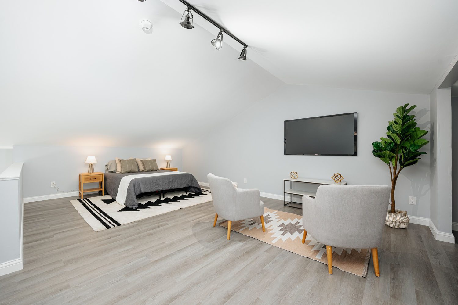 A cozy bedroom with a neatly made bed, a wooden desk, and a comfortable chair.