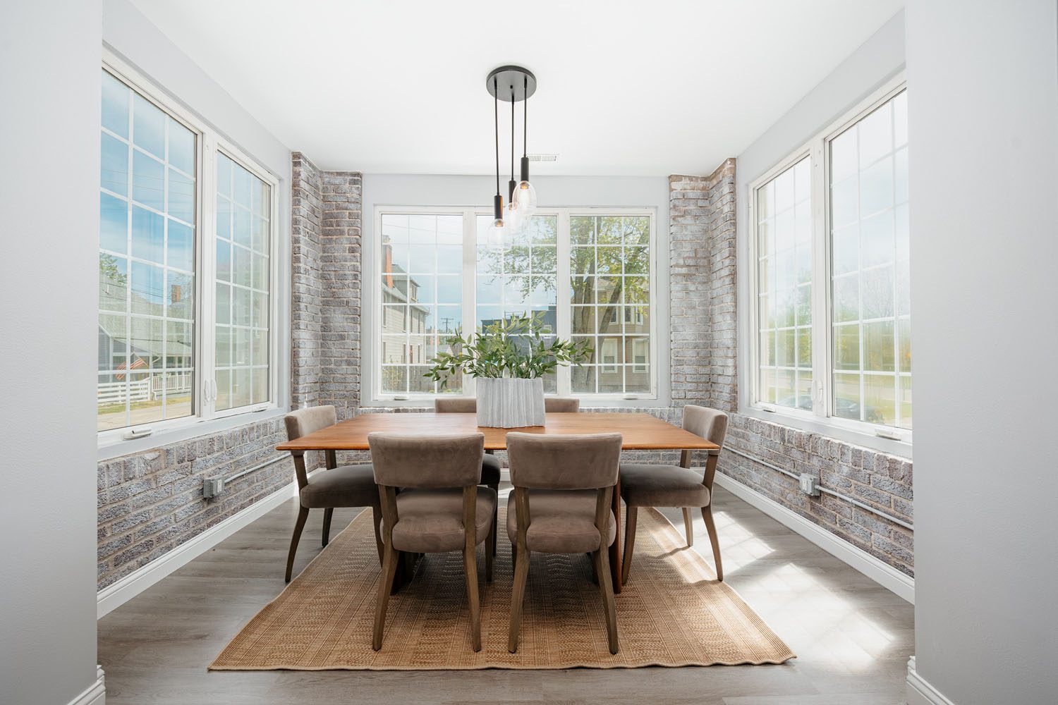 A dining room with white brick walls and windows, creating a bright and inviting atmosphere.