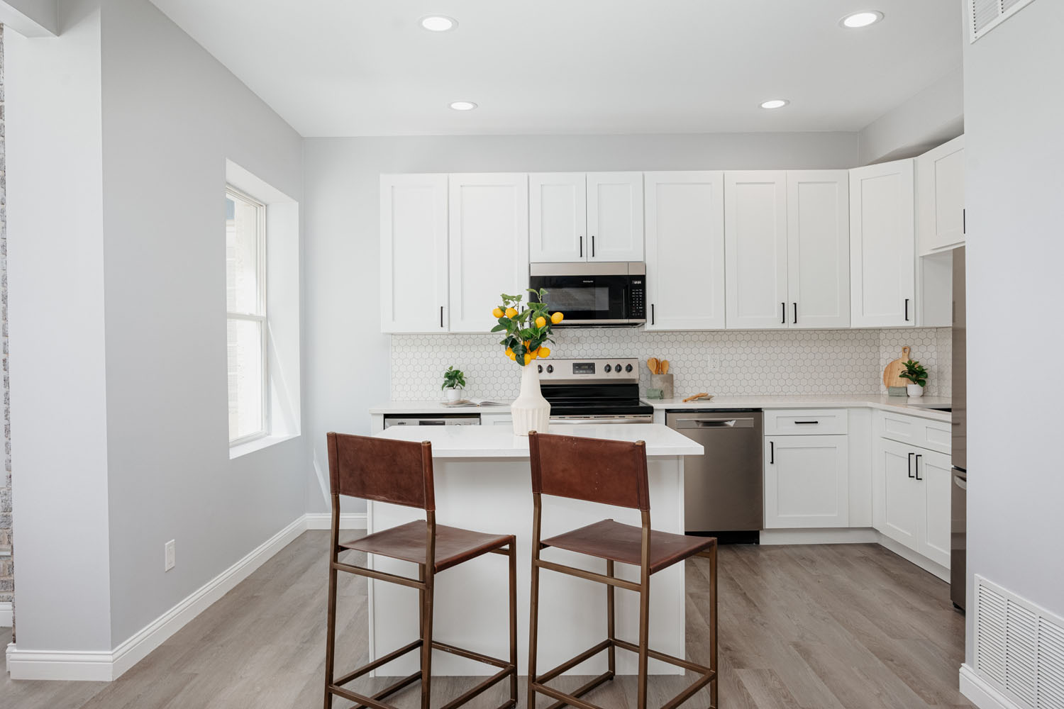 A kitchen with white cabinets and a microwave.